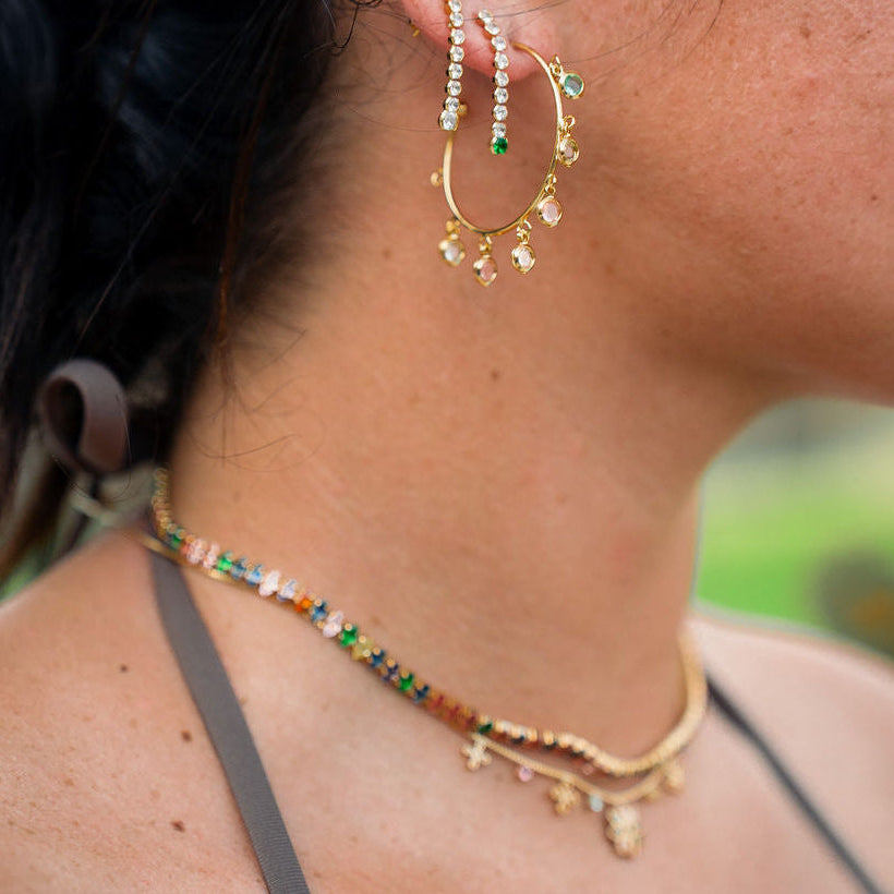 Close-up of a person wearing gold hoop earrings and a necklace with a blurred background