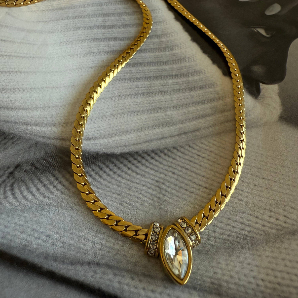 Gold chain necklace with a decorative clasp on a textured surface