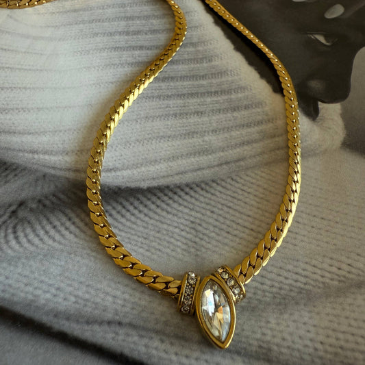 Gold chain necklace with a decorative clasp on a textured surface