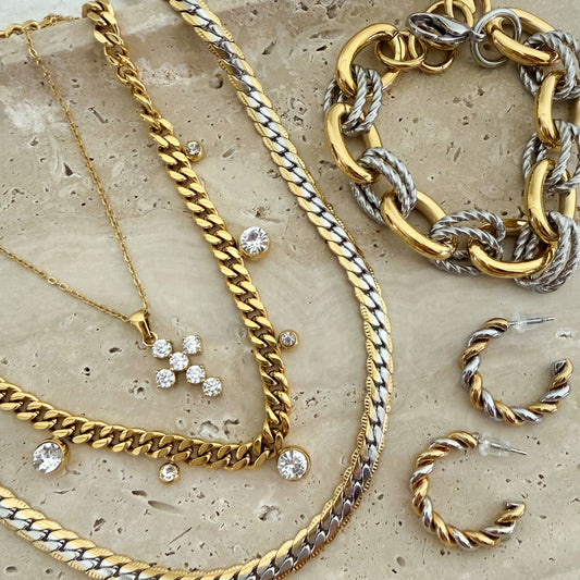 Gold and silver chain necklaces and bracelets on a textured surface